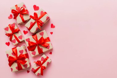 Top view photo of valentine day decorations gift box with red ribbon bow on colored background. Holiday gift boxes with top view.