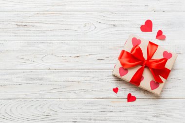 Top view photo of valentine day decorations gift box with red ribbon bow on colored background. Holiday gift boxes with top view.