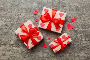 Top view photo of valentine day decorations gift box with red ribbon bow on colored background. Holiday gift boxes with top view.