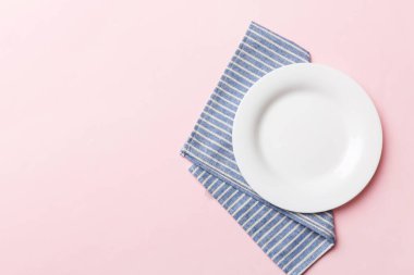 Renkli arka planda üst görünüm yiyecek için masa örtüsü üzerindeki boş yuvarlak beyaz tabak. Tasarımınız için boşluk olan peçeteye boş tabak.