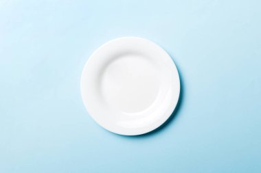 Renkli arka plan görüntüsünün üst görüntüsü yiyecek için boş yuvarlak beyaz tabak. Tasarımınız için alanı olan boş tabak.