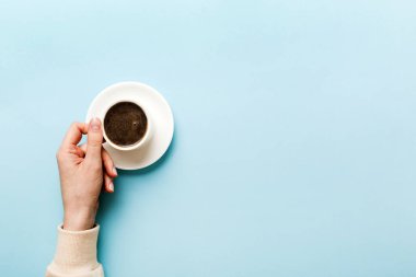 Renkli arka planda bir fincan kahve tutan minimalist stil bir kadın. Düz yatıyordu, üstten espresso fincanı. Metin için boş yer, kopyalama alanı. Kahve bağımlılığı. Üst manzara, düz uzanma.