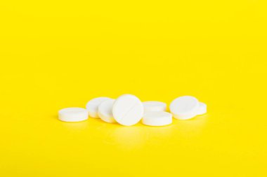 Renkli arka planda bir yığın beyaz hap. Tabletler masaya saçılmış. Kırmızı yumuşak jelatin kapsül yığını. Vitaminler ve beslenme takviyeleri konsepti.