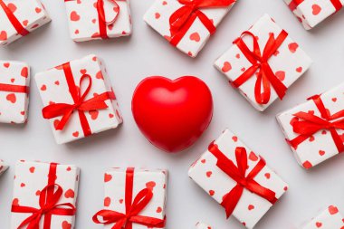 gift box with red bow and red heart on colored background . Top view. Flat lay.