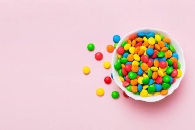 Renkli arka planda bir kasede çok renkli şekerler. Doğum günü ve tatil konsepti. Kopyalama alanı olan üst görünüm.