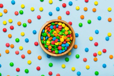 Renkli arka planda bir kasede çok renkli şekerler. Doğum günü ve tatil konsepti. Kopyalama alanı olan üst görünüm.