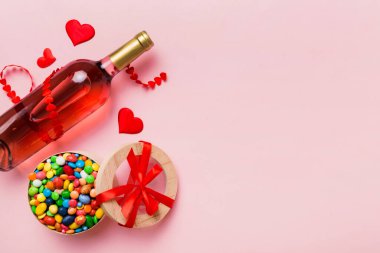 Sevgililer Günü için renkli arka planda bir şişe kırmızı şarap hediye ve çikolatalı. Kalp, hediye kutusuyla şekillendirilmiş çikolatalar fotokopi alanı ile üst görünüm.