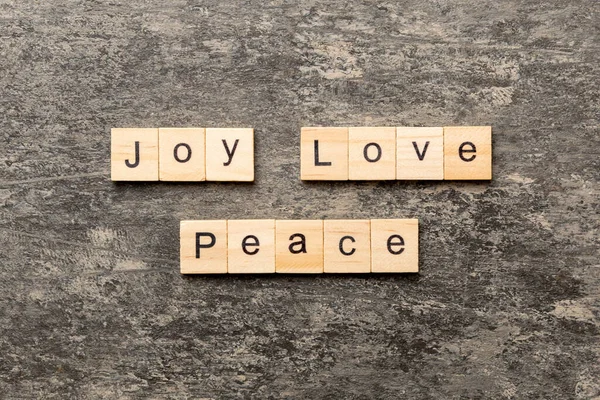 joy love peace word written on wood block. joy love peace text on cement table for your desing, concept.