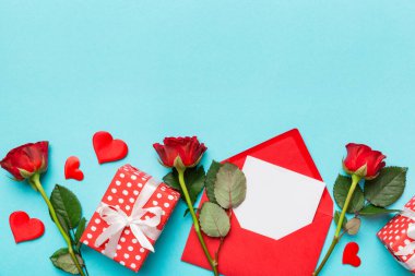 Zarflı sevgililer günü kompozisyonu, gül çiçeği ve kırmızı kalp masada. Üst manzara, düz yatış. Tatil kavramı.