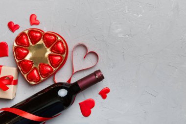 Sevgililer Günü için renkli arka planda bir şişe kırmızı şarap hediye ve çikolatalı. Kalp, hediye kutusuyla şekillendirilmiş çikolatalar fotokopi alanı ile üst görünüm.