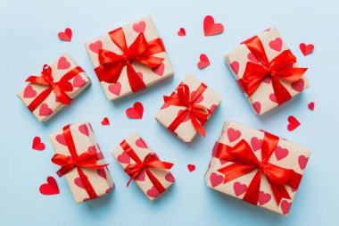 Top view photo of valentine day decorations gift box with red ribbon bow on colored background. Holiday gift boxes with top view.