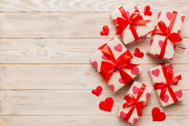 Top view photo of valentine day decorations gift box with red ribbon bow on colored background. Holiday gift boxes with top view.