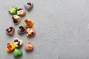 chocolate sweets in the form of a heart with fruits and nuts on a colored background. top view with space for text, holiday concept.