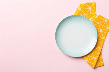 Renkli arkaplanda üst görünüm yiyecek için mavi tabak üzerinde boş. Tasarımınız için boşluk olan peçeteye boş tabak.