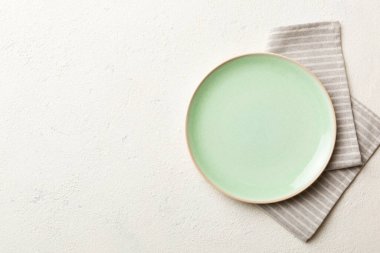 Renkli arka planda üst görünüm yiyecek için masa örtüsünün üzerinde boş yuvarlak yeşil tabak. Tasarımınız için boşluk olan peçeteye boş tabak.