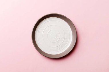 Renkli arka plan görüntüsünün üst görüntüsü yiyecek için boş yuvarlak beyaz tabak. Tasarımınız için alanı olan boş tabak.
