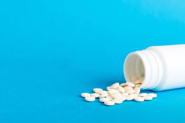 İlaç şişesi ve beyaz haplar arka plana dökülmüş. İlaçlar ve reçeteli haplar arka plandaydı. İlaç şişesinden beyaz ilaç ve haplar dökülüyor..