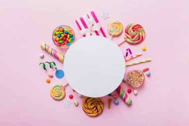 Tatil kompozisyonu yatıyordu. Kağıt boş, lolipop, renkli arka planda doğum günü süslemeleri. Üst görünüm, metin için boşluk kopyala.