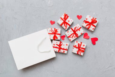 Gift boxes pop out from paper bag top view on colored background. bag packing handmade boxes fall out Concept of holidays, shopping, sale, discounts. Top view, flat lay.