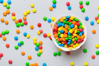 Renkli arka planda bir kasede çok renkli şekerler. Doğum günü ve tatil konsepti. Kopyalama alanı olan üst görünüm.