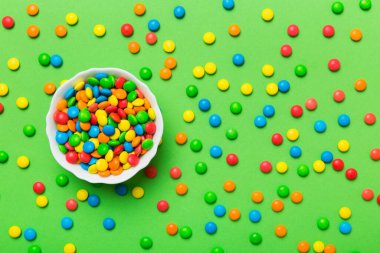 Renkli arka planda bir kasede çok renkli şekerler. Doğum günü ve tatil konsepti. Kopyalama alanı olan üst görünüm.