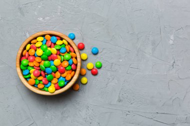 Renkli arka planda bir kasede çok renkli şekerler. Doğum günü ve tatil konsepti. Kopyalama alanı olan üst görünüm.