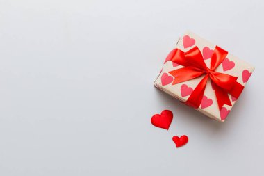 Top view photo of valentine day decorations gift box with red ribbon bow on colored background. Holiday gift boxes with top view.