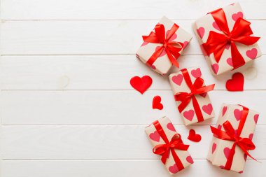 Top view photo of valentine day decorations gift box with red ribbon bow on colored background. Holiday gift boxes with top view.