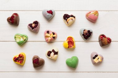 chocolate sweets in the form of a heart with fruits and nuts on a colored background. top view with space for text, holiday concept.