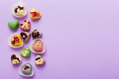 chocolate sweets in the form of a heart with fruits and nuts on a colored background. top view with space for text, holiday concept.
