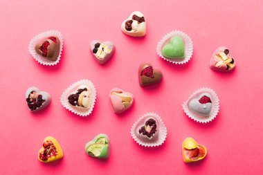 chocolate sweets in the form of a heart with fruits and nuts on a colored background. top view with space for text, holiday concept.