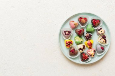 Plate with different chocolate on colored background. Assortment of fine chocolates top view vith copy space Health and obesity concept.