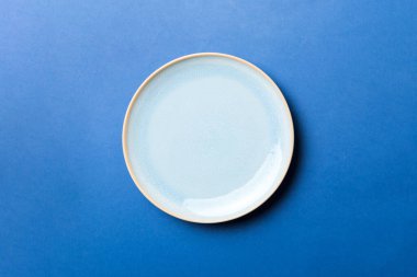 Renkli arka planın üst görüntüsü yiyecek için boş mavi tabak. Tasarımınız için alanı olan boş tabak.