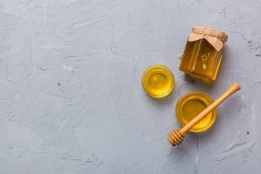 Renkli arka planda tahta çiselemeli cam bal kavanozu. Bal küpü ve dipper yükseklerde. Üst görünüm kopyalama alanı.