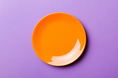 Renkli arka plan izole edilmiş üst görünüm yiyecek için boş yuvarlak orenge plaka. Tasarımınız için alanı olan boş tabak.