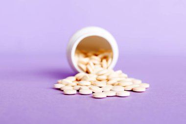 İlaç şişesi ve beyaz haplar arka plana dökülmüş. İlaçlar ve reçeteli haplar arka plandaydı. İlaç şişesinden beyaz ilaç ve haplar dökülüyor..