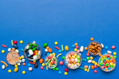 farklı renkte yuvarlak şekerler ve kavanozlar. Fotokopi alanı olan büyük çeşitlilikteki şeker ve şekerlerin üst görünümü.