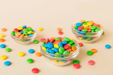 Renkli arka planda bir kasede çok renkli şekerler. Doğum günü ve tatil konsepti. Kopyalama alanı olan üst görünüm.