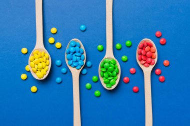 Renkli arka planda kaşık üzerinde renkli tatlı şekerler. Fotokopi alanı ile şekerleme dekoru üst görünümü.