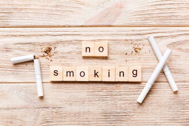 Sigara ve tahta bloklar, masa arkasında kırık sigara kum saati ile tütün günü yok, saat sağlığı konsepti. Sigarayı bırakma zamanı..