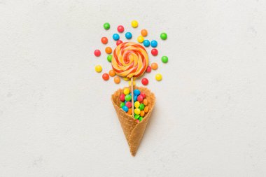 waffle cone full of assorted traditional candies falling out on colored background with copy space. Happy Holidays sale concept.