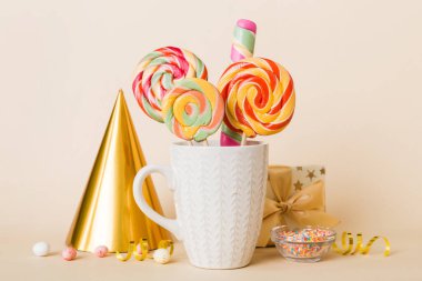 Masanın üzerinde açık arkaplanda renkli şekerler. Büyük kıvrımlı lolipoplar. Şekerci dükkanından leziz şekerlerle dolu yaratıcı bir kavanoz konsepti.