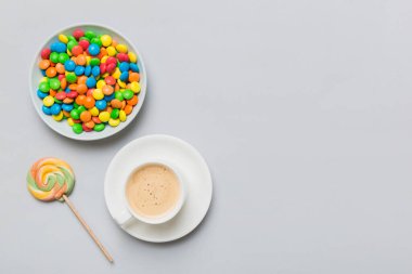 Coffee cup with chocolates and colored candy. Top view on table background with copy space.