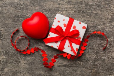 gift box with red bow and red heart on colored background . Top view. Flat lay.