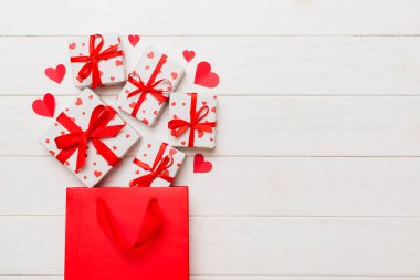 Gift boxes pop out from paper bag top view on colored background. bag packing handmade boxes fall out Concept of holidays, shopping, sale, discounts. Top view, flat lay.