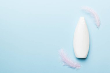 Pembe pastel arka planda, devekuşu tüyleriyle cilt bakımı serumları. Spa kozmetik ürünü, krem kavanozu, markalaşma modeli, fotokopi alanı olan üst görünüm.