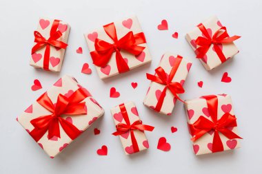 Top view photo of valentine day decorations gift box with red ribbon bow on colored background. Holiday gift boxes with top view.