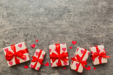 Top view photo of valentine day decorations gift box with red ribbon bow on colored background. Holiday gift boxes with top view.