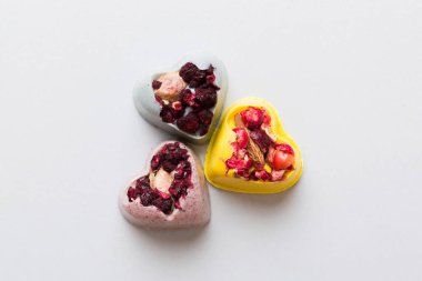 chocolate sweets in the form of a heart with fruits and nuts on a colored background. top view with space for text, holiday concept.