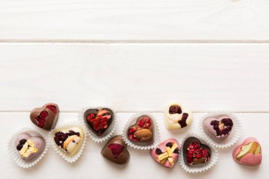 chocolate sweets in the form of a heart with fruits and nuts on a colored background. top view with space for text, holiday concept.